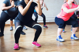 Women in fitness studio squatting.